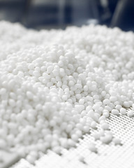 Vertical closeup of a white plastic polymer granule in a laboratory on a blue background.