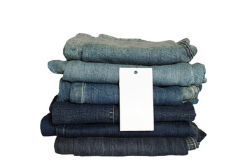 A stack of new jeans with white paper tag mockup and copy space isolated on white