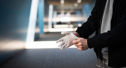 Mann in der Öffentlichkeit zieht Gummihandschuhe an um sich vor Viren und Bakterien zu schützen 