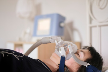 A woman sleeping in her bed with a ventilator