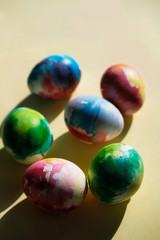 Colorful Easter eggs in watercolor style on a yellow background close-up. Easter concert. Bright colorful spots. Bright sunlight, direct rays of the sun.