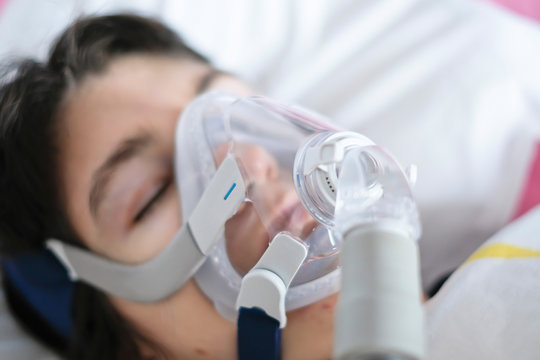 A woman sleeping in her bed with a ventilator