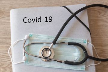 File with covid-19 written on it, medical mask and stethoscope