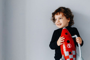 portrait of a little boy with a red spaceship in his hands on a gray background
