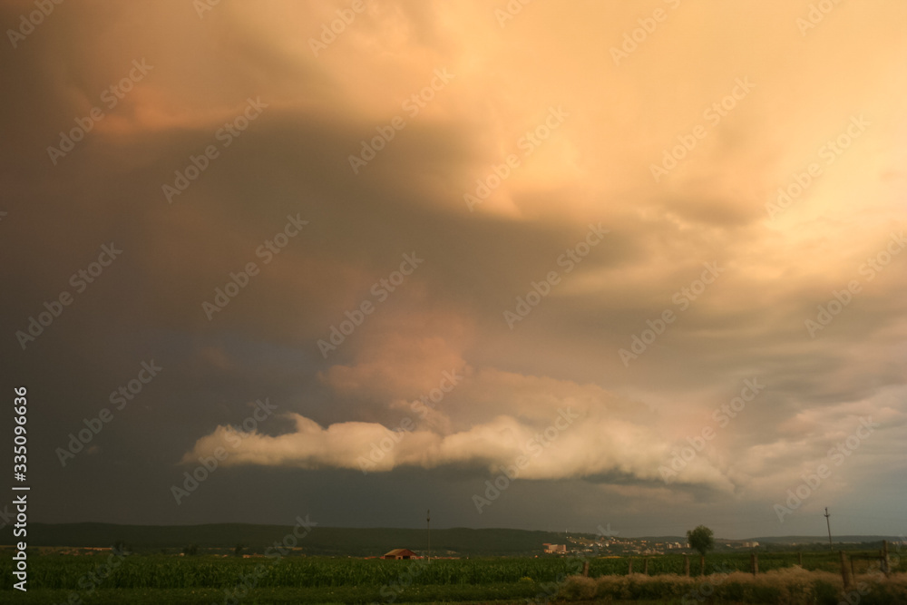 Wall mural Threatening stormcloud in Transylvania, Romania is illuminated by the setting sun