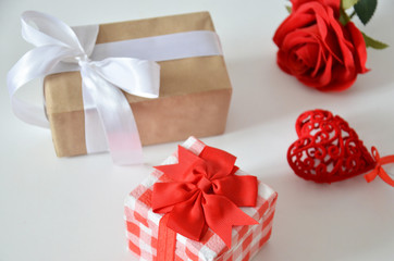Homemade red present box with a gift tied with a ribbon, on a background a red rose on a white background, mothers day copy space of gifts for Christmas, valentines day, happy birthday, female hand.