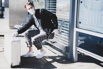 Ein Mann wartet auf dem Bahnsteig auf einen Zug, er trägt einen Mundschutz und Gummihandschuhe um sich vor dem Coronavirus zu schützen  - obrazy, fototapety, plakaty