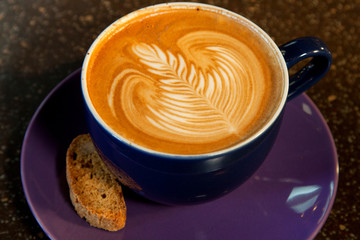 Caffe Latte Coffee with Rosetta Design in Ceramic Mug with Biscotti on Plate