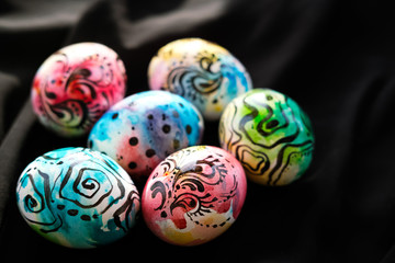 Colorful Easter eggs with a graphic pattern lie on black textiles. Easter concert