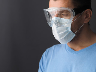 Male doctor wearing protective Mask and Goggles. Place for text. Dark background..