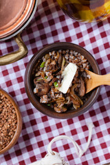 Traditional russian simple meal: cooked buckwheat porridge with brown butter in clay pot. Healthy food, low calories, easy to cook. Copper pan, wooden backround, close up. Top view flat lay layout