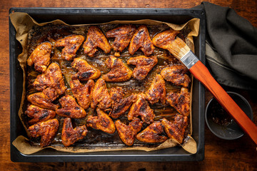 Grilled chicken wings in barbecue sauce in baking tray.