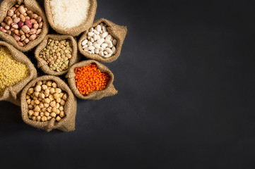 Obraz na płótnie Canvas Different type of raw dry legumes composition. White beans, lentils, bulgur, chickpeas, kidney beans, corns, rice, Mix organic legume concept, copy space