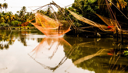 Ancient Chinese nets of fishermen that are still used and reflected on the sea, together with fishermen and diverse local people, in a calm rural village landscape of the southern Indica, Asia