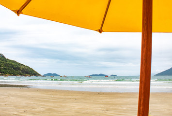 Guarda-sol  amarelo e barcos no mar na Praia do Pântano do Sul, Florianópolis - SC, Brasil