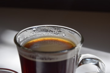 glass cup of coffee with a shadow on a glossy surface