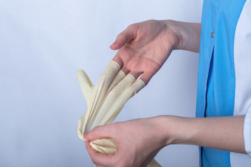 a nurse in uniform removes disposable rubber gloves from her hand. gloves are designed to protect against microbes, bacteria, diseases, virus and coronavirus infection upon contact and shaking hands
