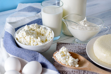  bottle and a glass of milk, sour cream, cottage cheese, eggs, cheese, a towel on a white table