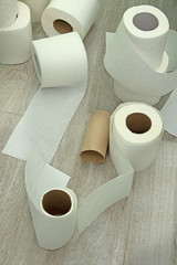 toilet paper on the floor made of ceramic tiles. New and used rolls of white toilet paper.