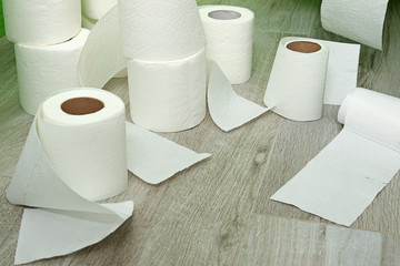 toilet paper on the floor made of ceramic tiles. New and used rolls of white toilet paper.