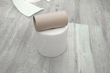 toilet paper on the floor made of ceramic tiles. New and used rolls of white toilet paper.