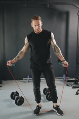 a fitness trainer stands with a skipping rope in his hands in the gym