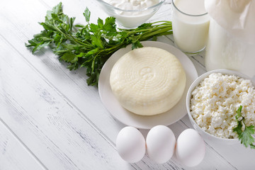 cottage cheese, sour cream, yogurt, parsley, herbs, white eggs, towel on a white wooden background, dairy products,