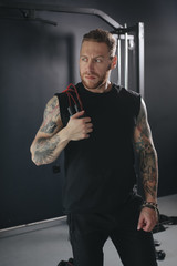 a fitness trainer stands with a skipping rope in his hands in the gym