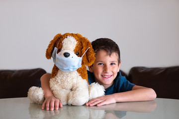 Little boy is playing with a plush toy dog in a medical mask. The concept of protection during quarantine
