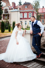 Naklejka premium The bride and groom walk together in the park. Charming bride in a white dress, the groom is dressed in a dark elegant suit.
