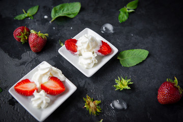 strawberries with whipped cream on a plate, mint leaves on a black , fresh berries, dessert