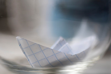 Paper checkered boat in a cup with water. Selective sharpness.