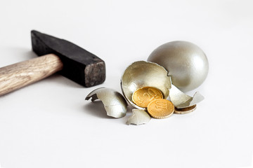 broken golden egg, shell, hammer and coins on a white background, crisis concept, last money,