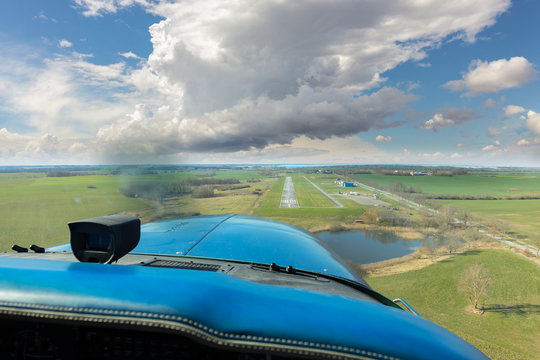 A landing approach in a cloudy sky to the small airport on the German island of R&uuml;gen in the Baltic Sea. It is winter and the pilot has trouble landing in strong winds. A helicopter is on the ground.