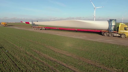 Building process of wind energy power tower mill, under construction. Transportation, installation of rotor blades. Green, clean, renewable energy. Aerial footage.