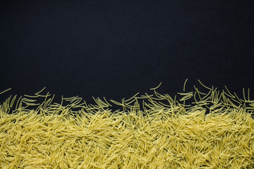 Dry pasta scattered on a black background close up with copy space. Food photo.