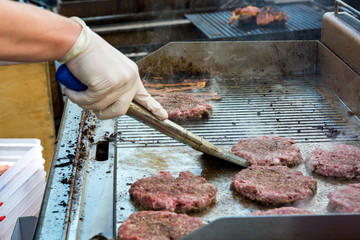 Chef preparing delicious burgers and flipping them on grill.