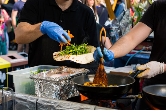 Cheff preparing tasty vegetarian kebab dish on food stand.