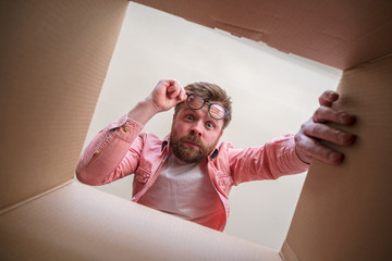 Man looks in bewilderment at the newly unpacked box with the parcel. Delivery error or defective...