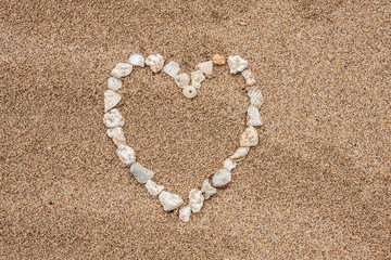 A symbolic heart made of sea stones and shells in sand