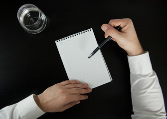 A man shows a pen in a white notebook