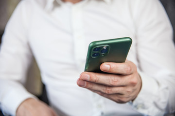A man in a white shirt holds a phone in his hand and searches for important information