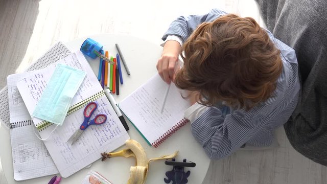 Boy writing in notebook during online education