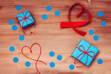 Blue gift boxes, red hearts and confetti on wooden table top, flat lay, copy space. Background for Father's Day, Mother's Day or other holiday