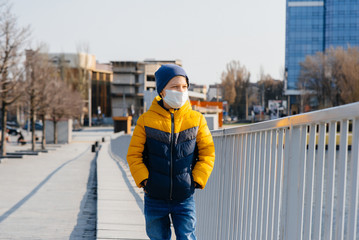 A boy stands on a gray background in a mask during a quarantine with free space. Quarantine in the mask