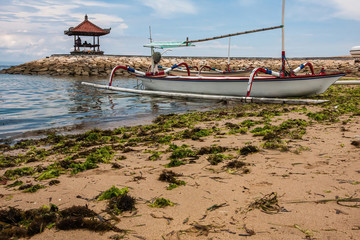 A traditional Balinese outrigger canoe, jukung, at rest on a beach