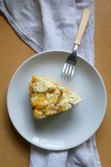Potato, egg, ham and vegetable pie on a wooden table. Top view.