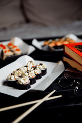 Sushi, Asian food, rolls, Philadelphia, sesame. Restaurant food. Fast food. With books, study, glasses for sight.