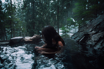 Sad woman sitting in an outdoor hot spring in British Columbia Canada