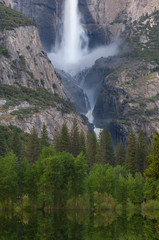 Spring landscape of Yosemite Falls captured with motion blur and with reflections in the flooded Merced River, Yosemite National Park, California, USA